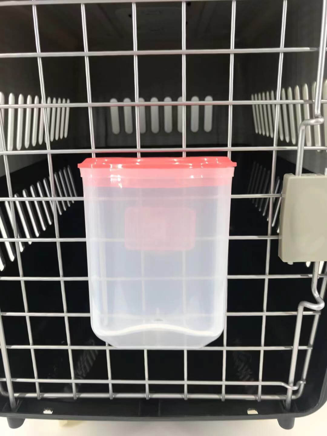 Water dispenser attached to a pet carrier, ideal for providing easy access to fresh water for small animals.