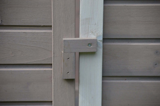 Close-up of wooden latch on a grey chicken coop door, showcasing quality craftsmanship and durable design for secure closure.