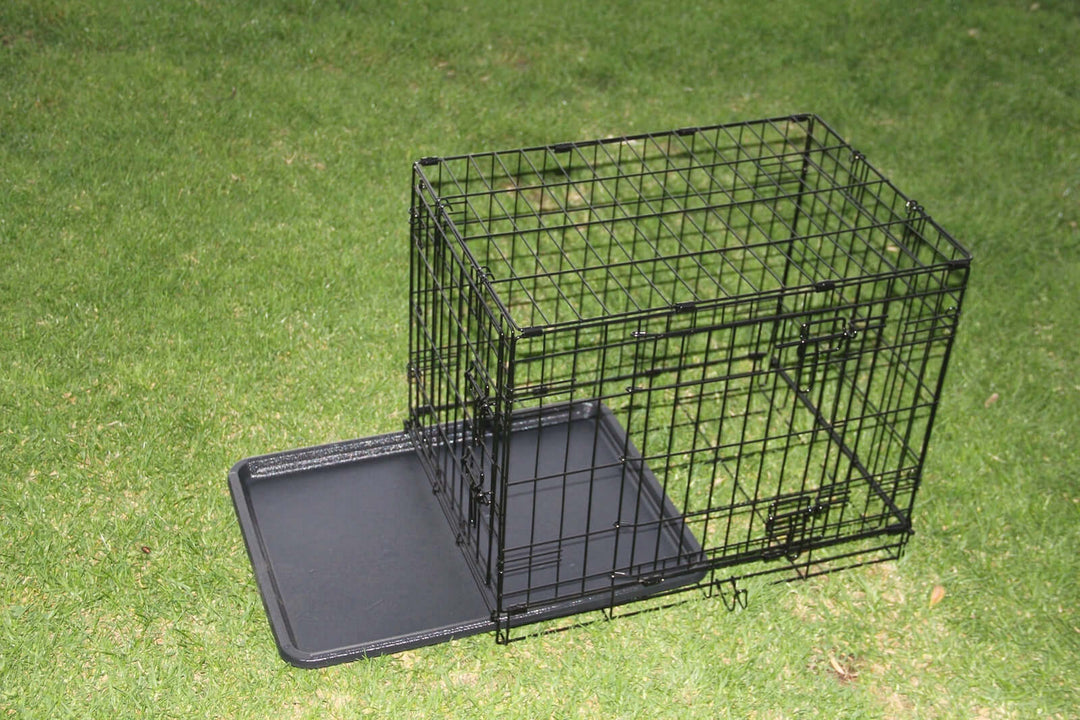 Collapsible metal dog crate with removable tray, perfect for pets like dogs, cats, and rabbits in a grassy setting.