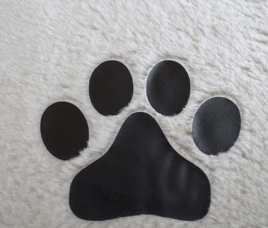 Black pet paw print on soft beige surface for pet-friendly decor or products