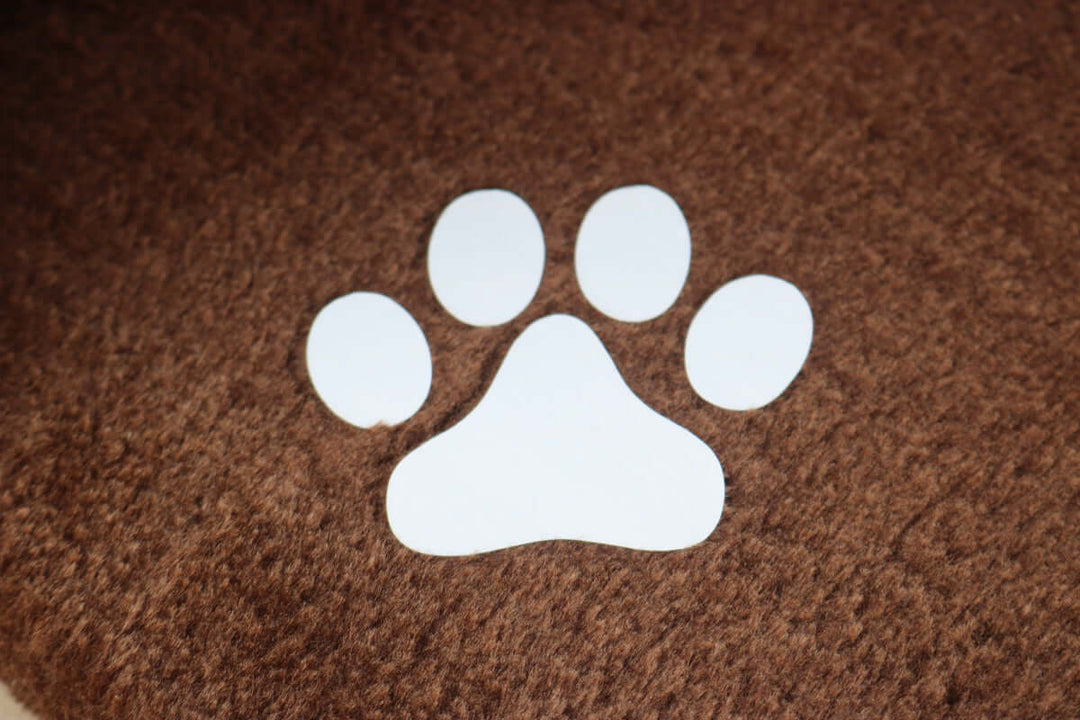 White paw print design on a brown textured background, symbolizing pet-friendly products.