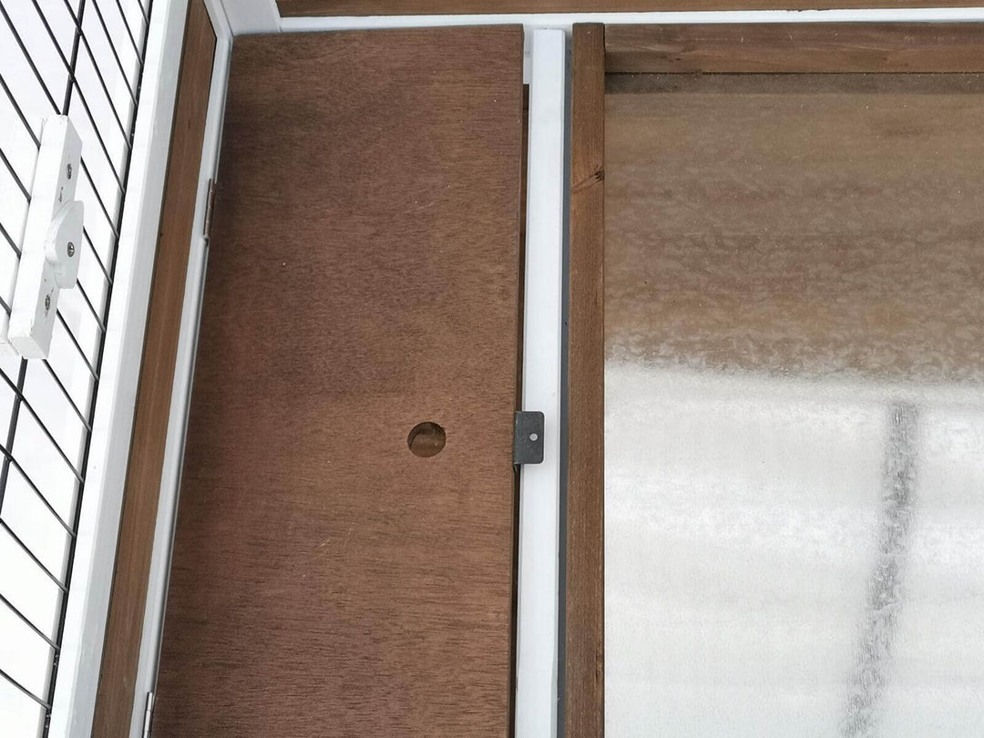 Close-up of interior wood panel and door mechanism in a rabbit hutch for easy access and cleaning.