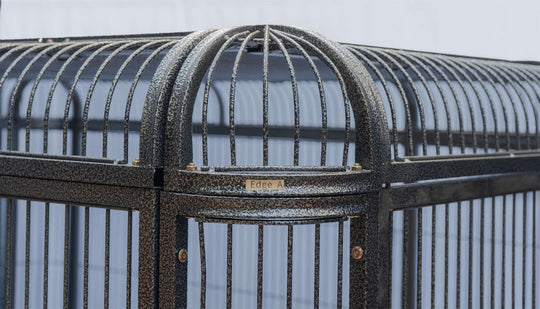 Close-up of the top frame of a black-wrought iron bird and pet cage with secure bars and labeled edges.