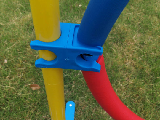 Close-up of YES4PETS adjustable dog agility jump tire connector in vibrant blue, yellow, and red colors on grass.