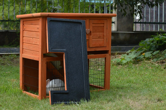 Double storey rabbit hutch with pull-out tray in a grassy yard, ideal for small animals like rabbits and guinea pigs.