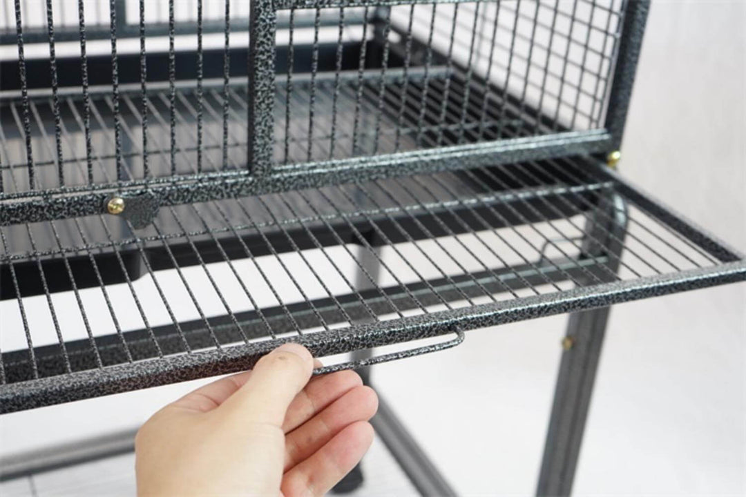 Hand demonstrating the slide-out bottom tray of a YES4PETS large bird cage, showcasing easy cleaning features.