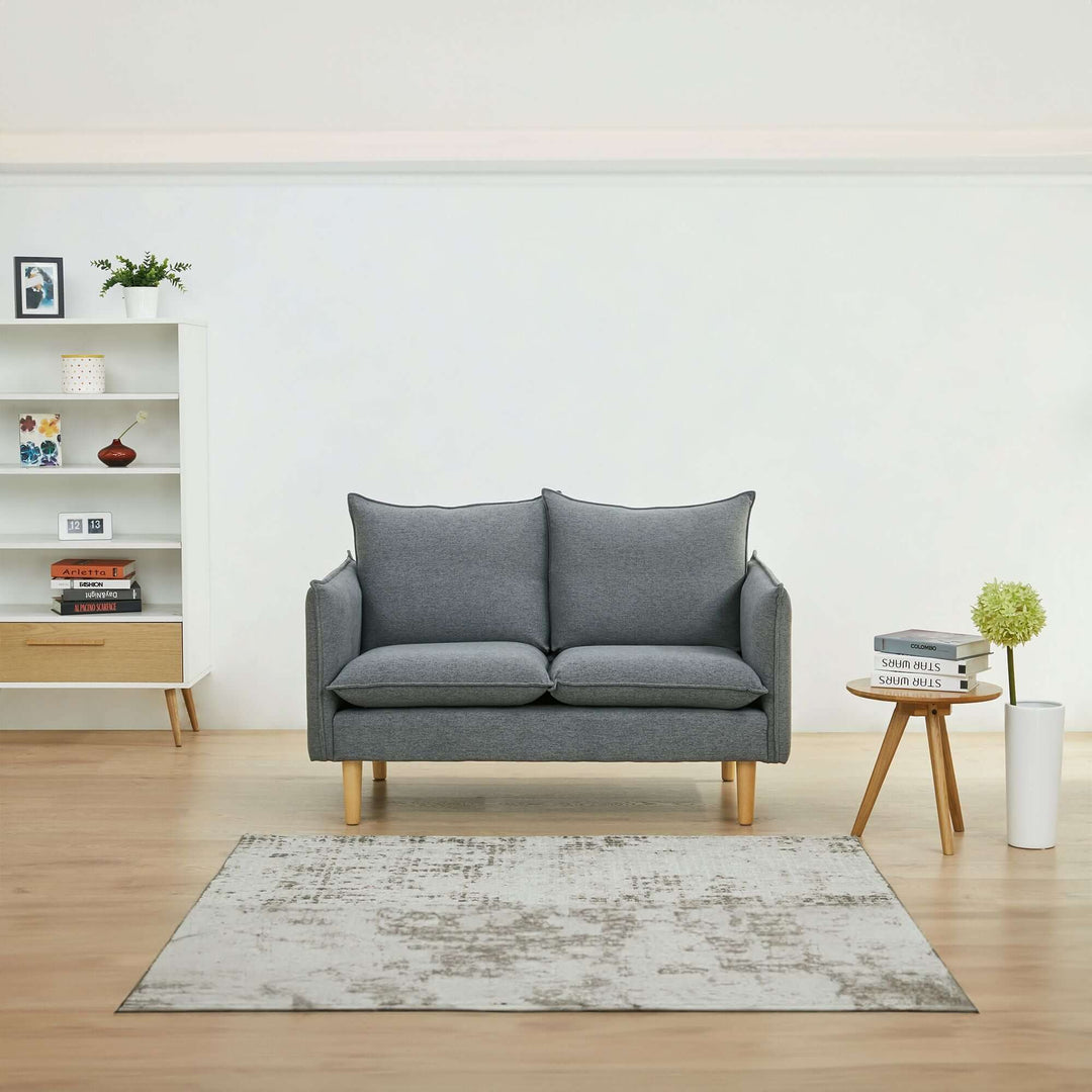 Dark grey 2-seater fabric sofa in a modern lounge with natural wood legs, surrounded by stylish home decor.