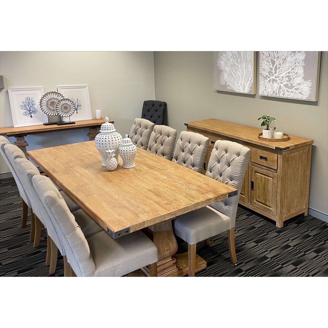 Dining area with solid mango wood buffet table and dining set with beige cushioned chairs in French provincial style.