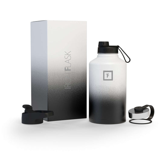 Iron Flask 64oz Wide Mouth Bottle with Spout Lid in black and white gradient, includes packaging and lid accessories.