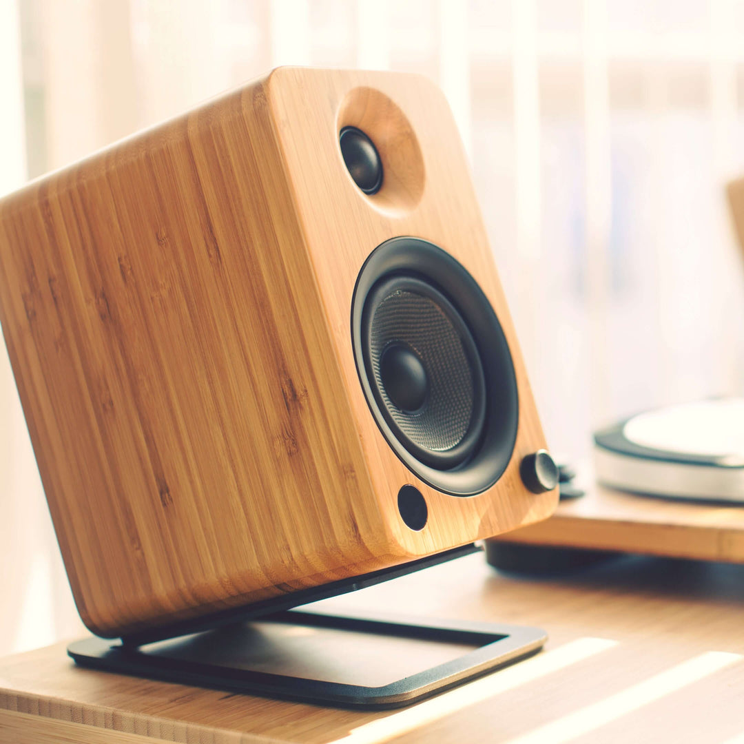 Kanto YU4 bamboo powered bookshelf speaker showcasing quality sound and stylish design on a wooden table.