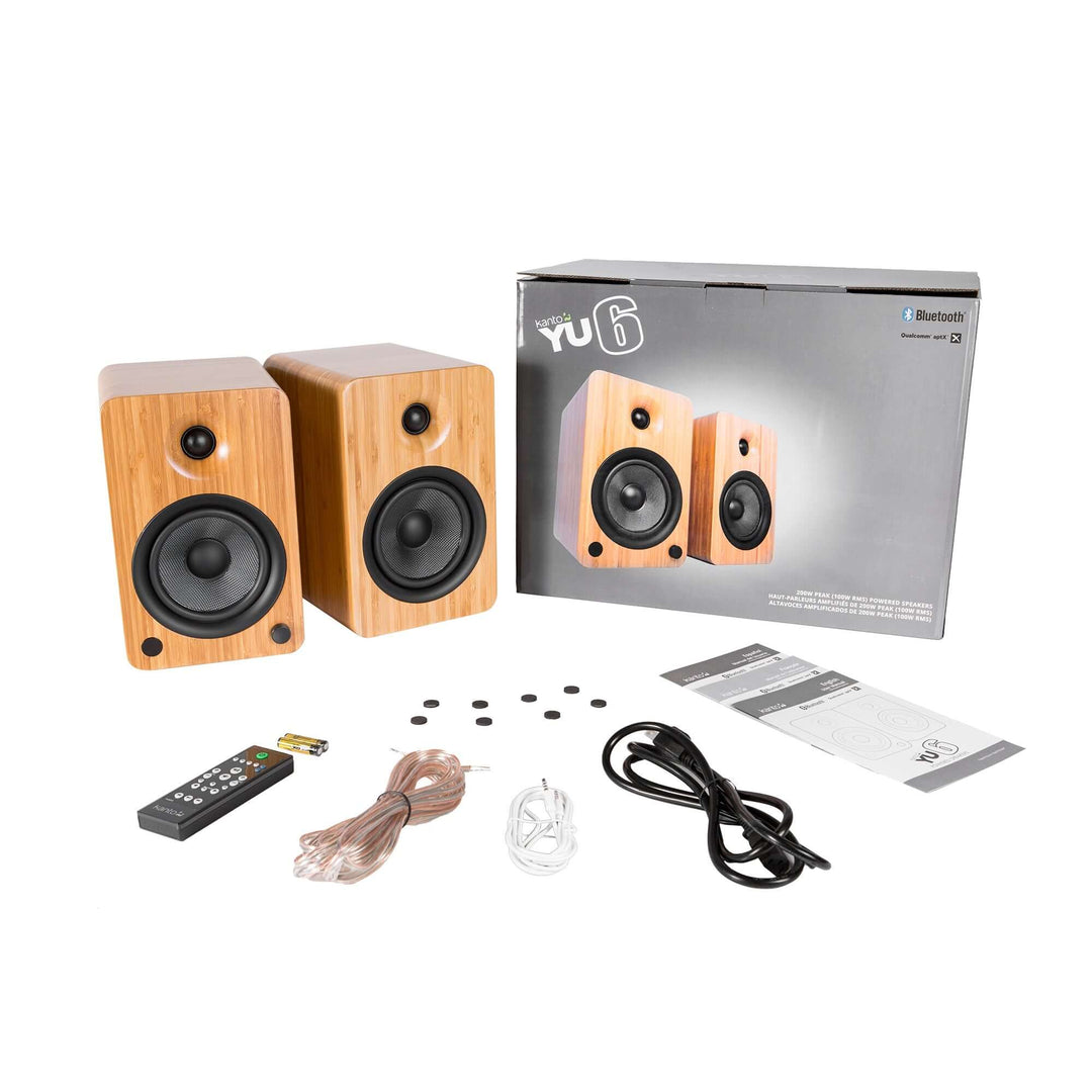 Kanto YU6 Bamboo powered bookshelf speakers set with remote, cables, and manual for quality sound and Bluetooth connectivity.