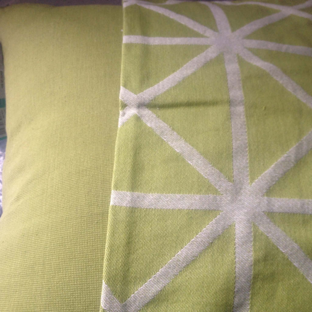 Stylish green cushion cover featuring a textured solid side and geometric pattern side for modern home decor.