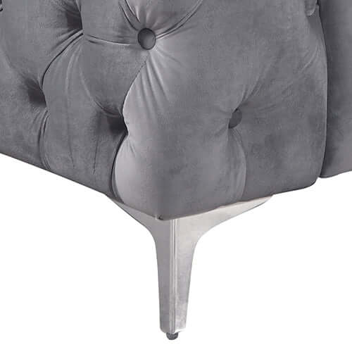 Close-up of grey velvet fabric with button tufting and sleek metal legs of a stylish 3 seater sofa.