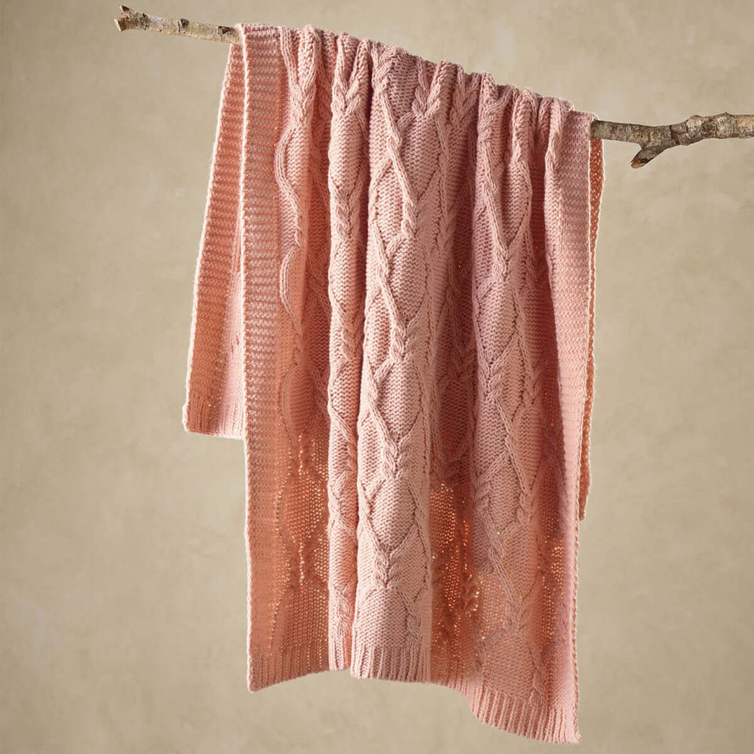 Affordable blush knitted throw rug, 130 x 160 cm, draped over branch, ideal for DIY luxe decor, quality acrylic fabric.