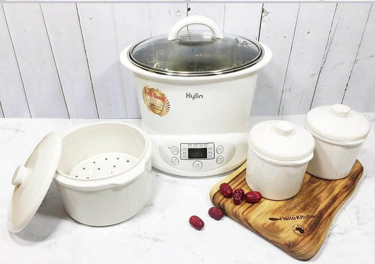 Kylin Electric Slow Cooker with ceramic pot and steaming containers on a wooden board, showcasing quality kitchen cookware.