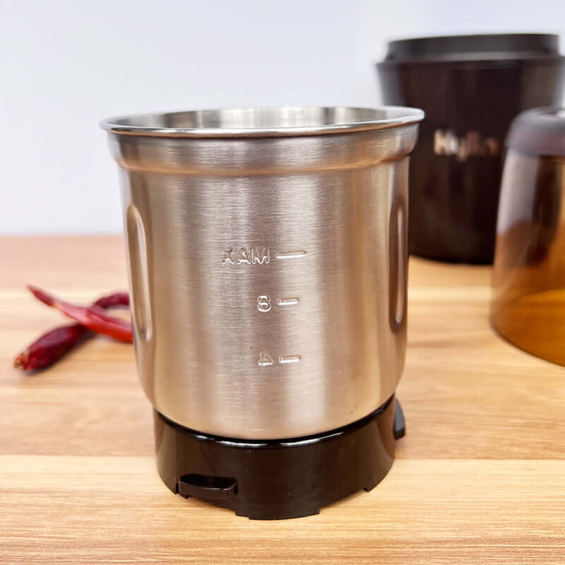 Stainless steel grinding cup of Kylin Electric Multi-Purpose Grinder on kitchen counter with red chilies.