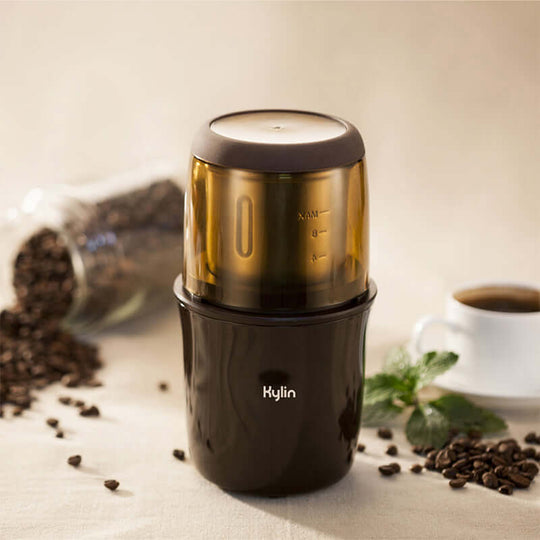 Kylin Electric Multi-Purpose Grinder with transparent lid, surrounded by coffee beans and a cup of coffee.