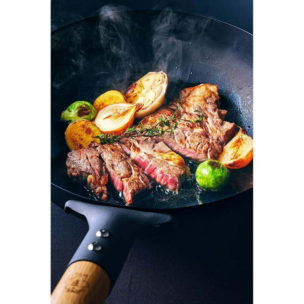 Juicy steaks and vegetables sizzling in a Takumi Premium Magma Plate cast iron wok, showcasing quality cooking experience.