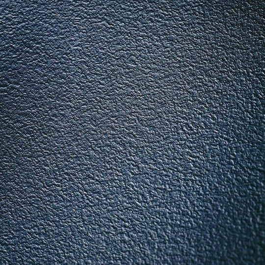 Close-up of textured dark leather surface, showcasing a luxurious and sophisticated material.