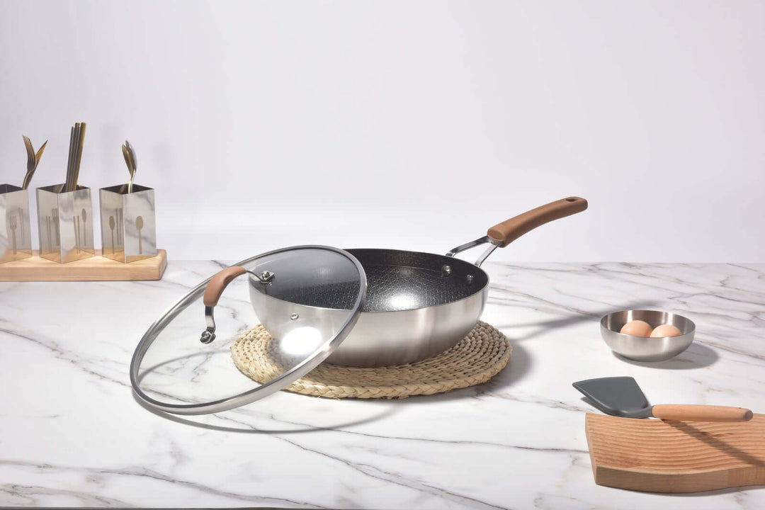 Kylin 3 Layer Stainless Steel Non Stick Noka Wok with lid on a marble countertop, showcasing affordable quality kitchenware.