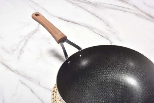 Kylin 3 Layer Stainless Steel Non Stick Wok with a comfortable handle on a marble countertop.