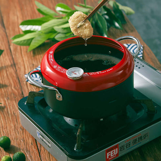 Justcook 20cm fryer pot with a thermometer, showcasing oil drainage and healthy frying, placed on a stove with fresh ingredients.