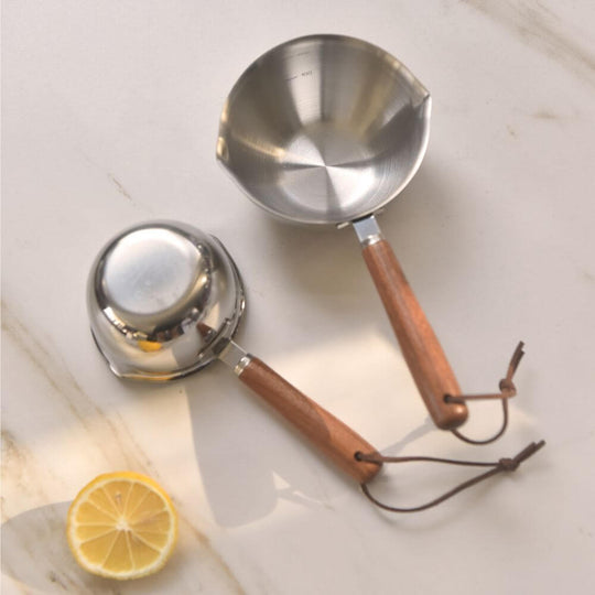 Kylin 304 stainless steel oil poured pot with wood handle next to a lemon on a marble surface.