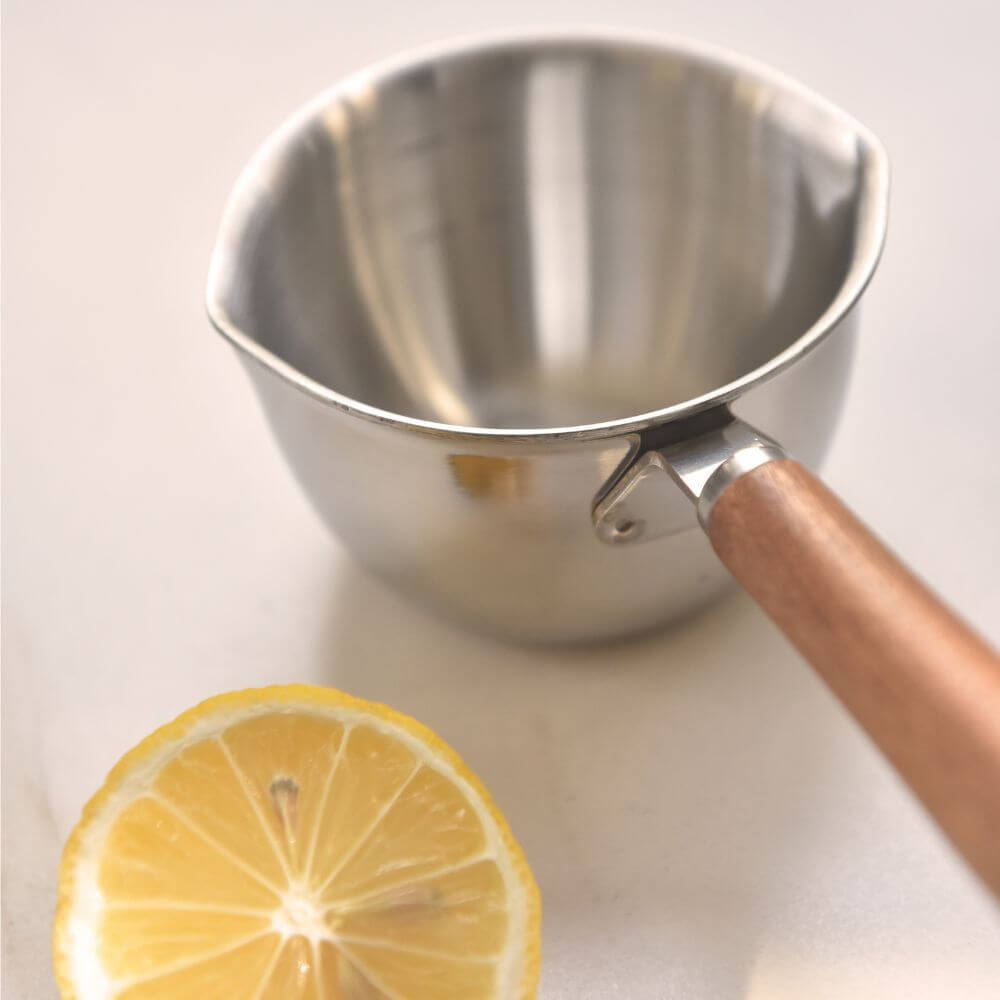 Kylin 304 stainless steel oil poured pot with wood handle next to a lemon slice on a light surface.