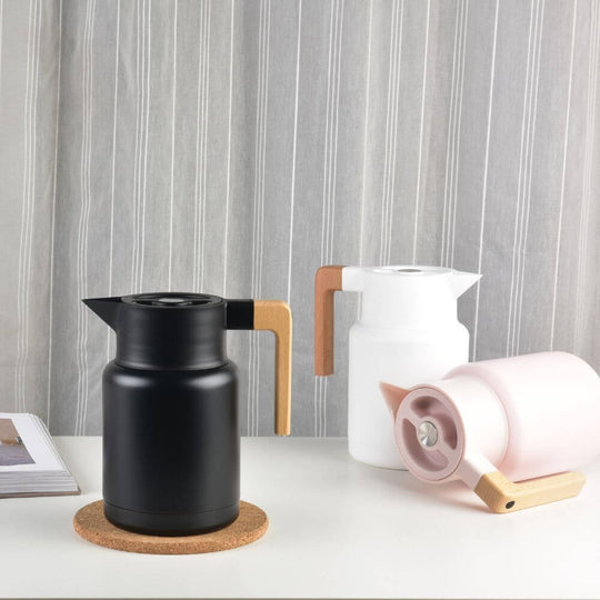 Stylish Kylin stainless steel vacuum jugs in black, white, and pink with wooden handles on a countertop.