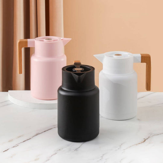 Stylish vacuum jugs in black, pink, and white with wooden handles on a marble surface. Perfect for hot or cold beverages.