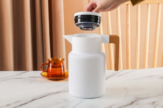 Kylin 304 stainless steel Japanese vacuum jug being filled, featuring a sleek white design and wooden handle.