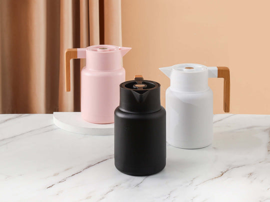 Stylish Kylin stainless steel vacuum jugs in pink, black, and white with wooden handles on a marble surface.