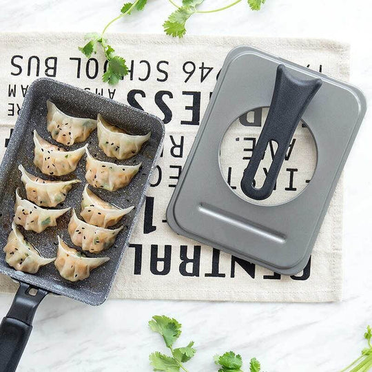 Justcook grey Tamago fry pan lid with dumplings on a textured cloth, showcasing affordable quality for DIY cooking.