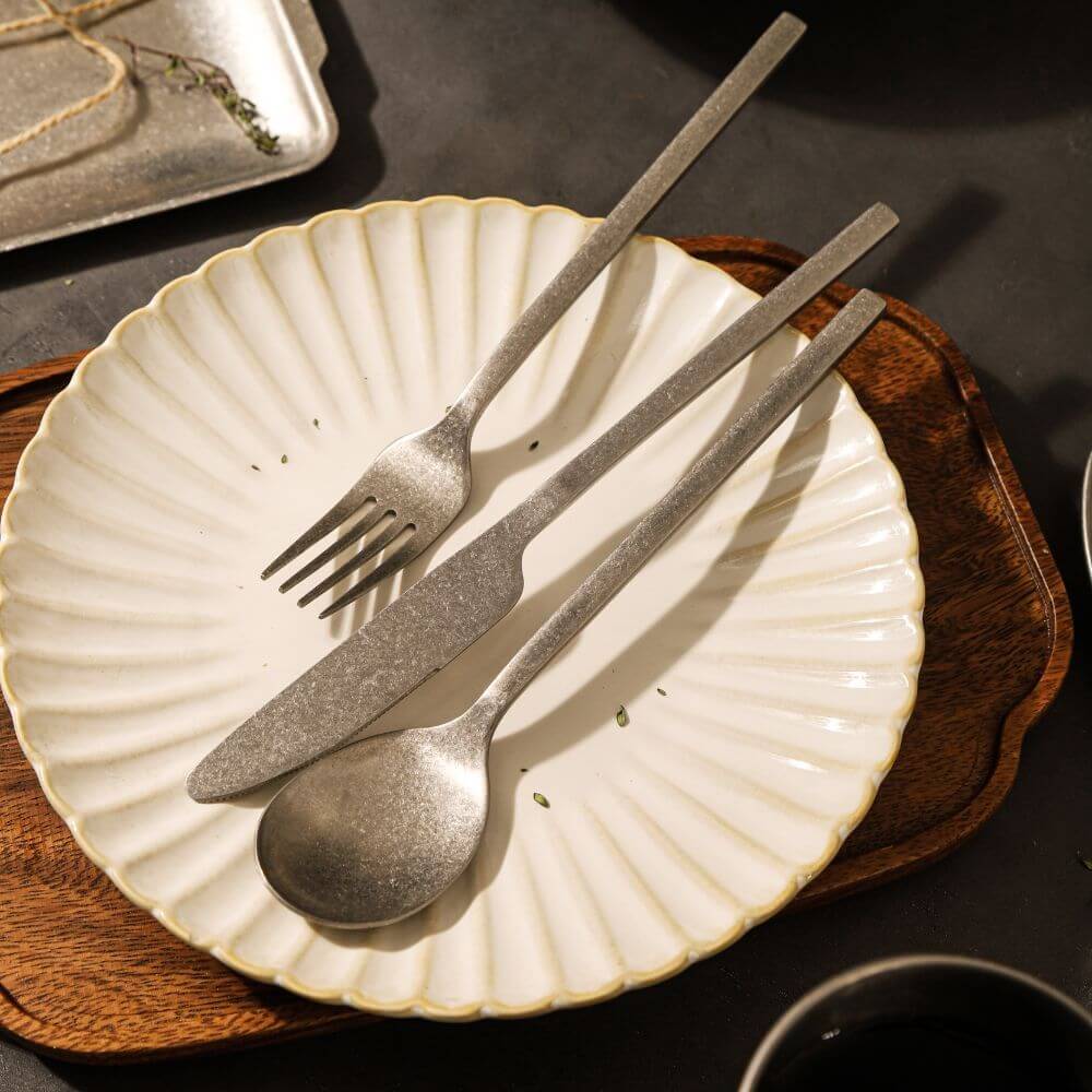 Elegant Kylin 304 stainless steel fork, knife, and spoon set on a decorative plate for stylish dining.