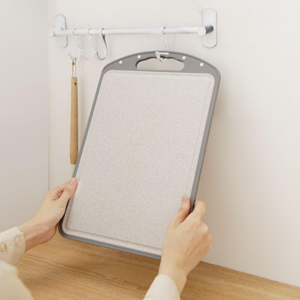 Person lifting a versatile cutting board from a wall rack in a modern kitchen setting.