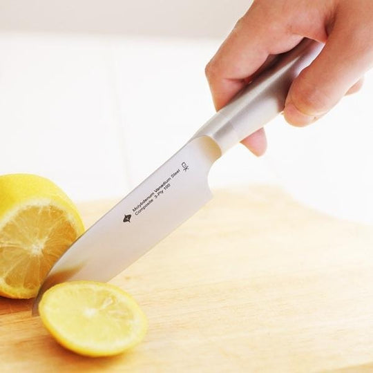 Quality Yanagi Chef Knife slicing a lemon on a wooden cutting board, showcasing affordable luxury for DIY cooking.