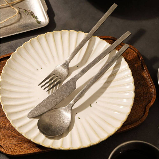 Elegant stainless steel cutlery set on a decorative plate, enhancing a stylish dining experience.