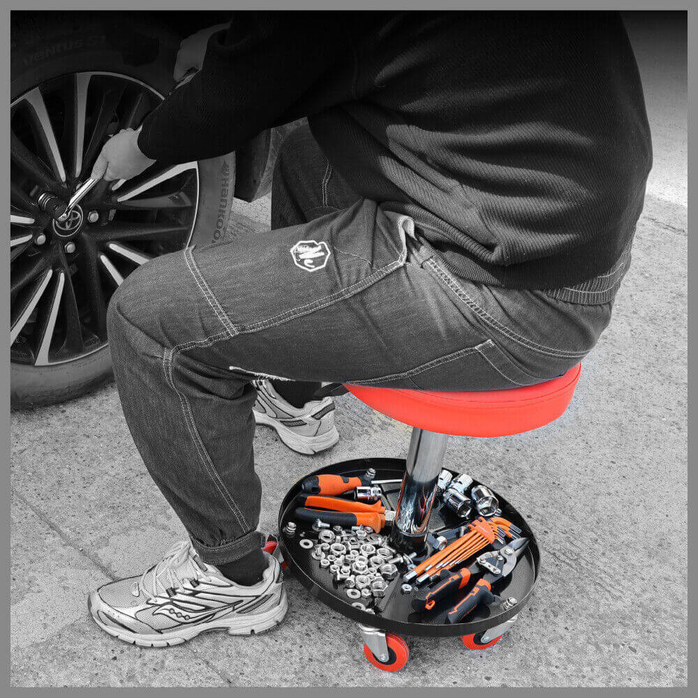 Man using SEDY pneumatic roller seat with tools while changing a tire, showcasing affordable quality and easy mobility.