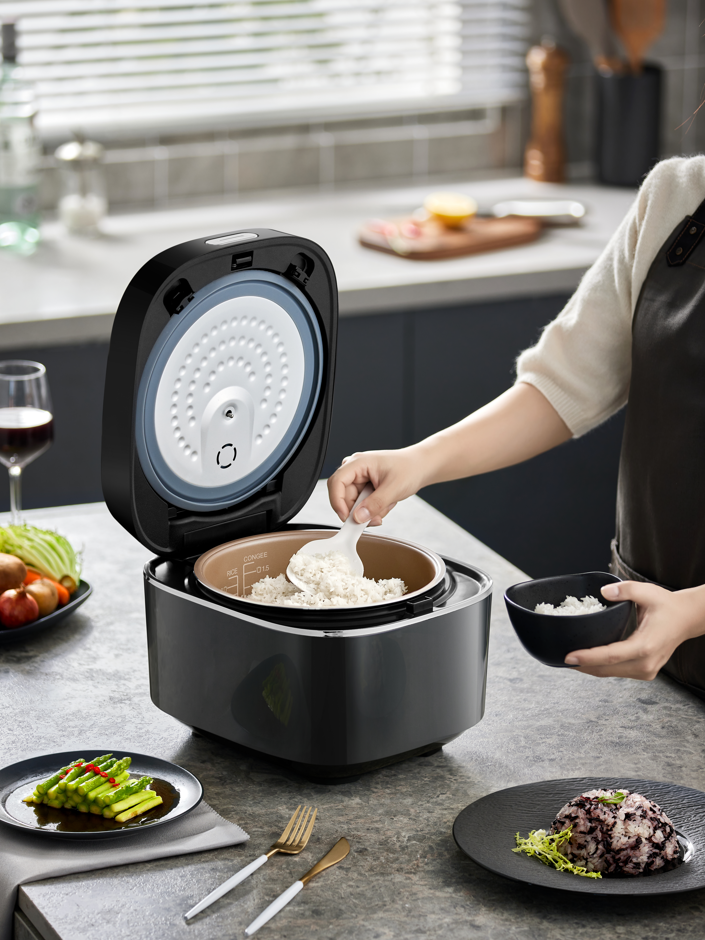 Person using BEAR 4L Intelligent Power Heating Rice Cooker DFB-Q40R5 in a modern kitchen for cooking rice.