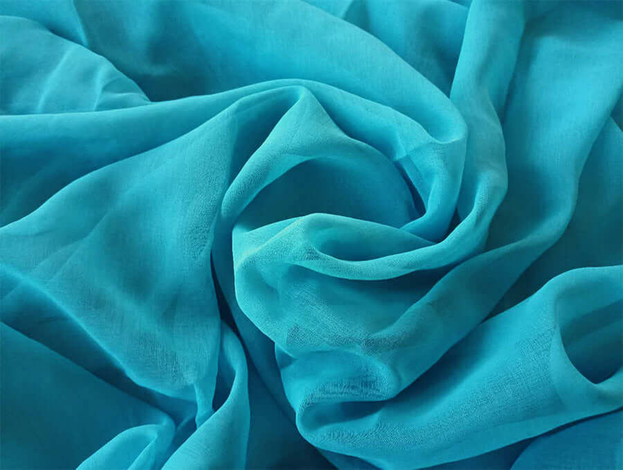 Close-up of lake blue sheer voile fabric, lightweight and perfect for DIY curtains, showcasing its soft texture and vibrant color.