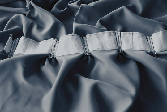 Close-up of high-quality pinch pleat curtain hooks on soft, grey blue fabric, showcasing luxury DIY curtain design.