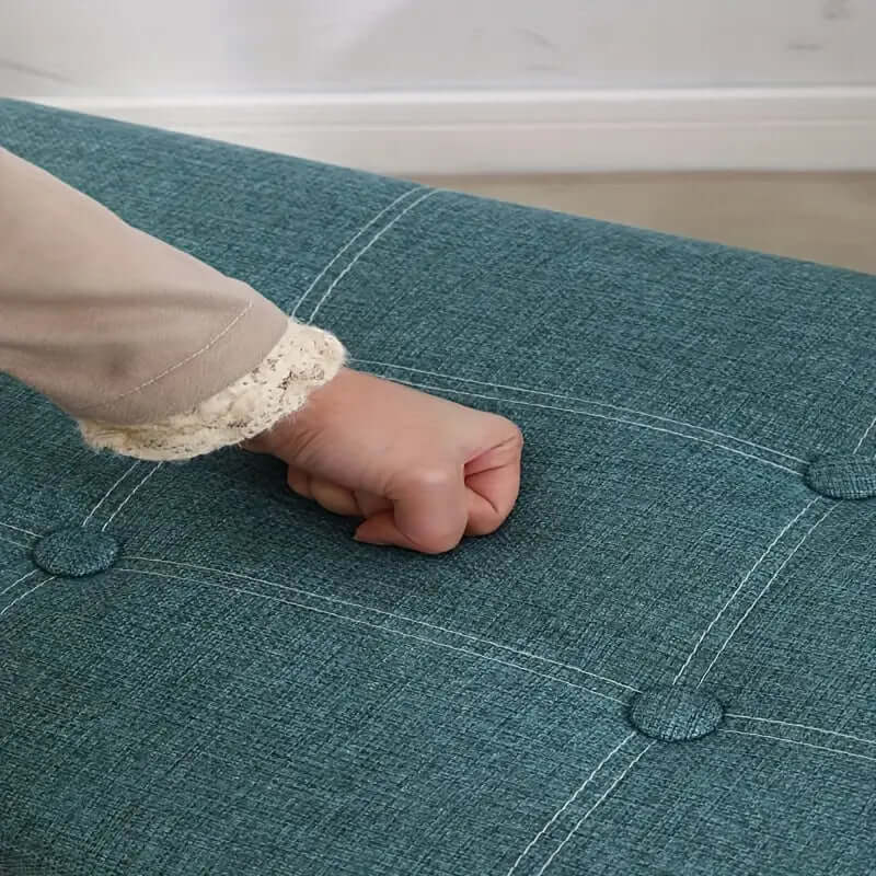 Close-up of a hand pressing down on the durable Morandi green storage stool fabric, showcasing its quality and texture.