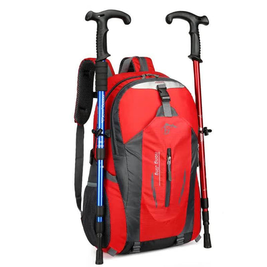 Red waterproof hiking backpack with multi-compartment design and trekking poles, perfect for affordable outdoor travel and camping.