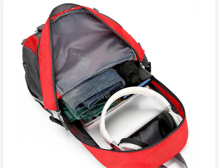 Open compartment of a red lightweight backpack showcasing organized items including jeans and headphones for travel convenience.