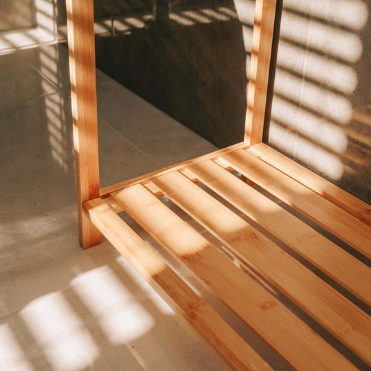 Close-up of a bamboo towel rack's bottom shelf with shadows, showcasing an elegant bathroom organizer.