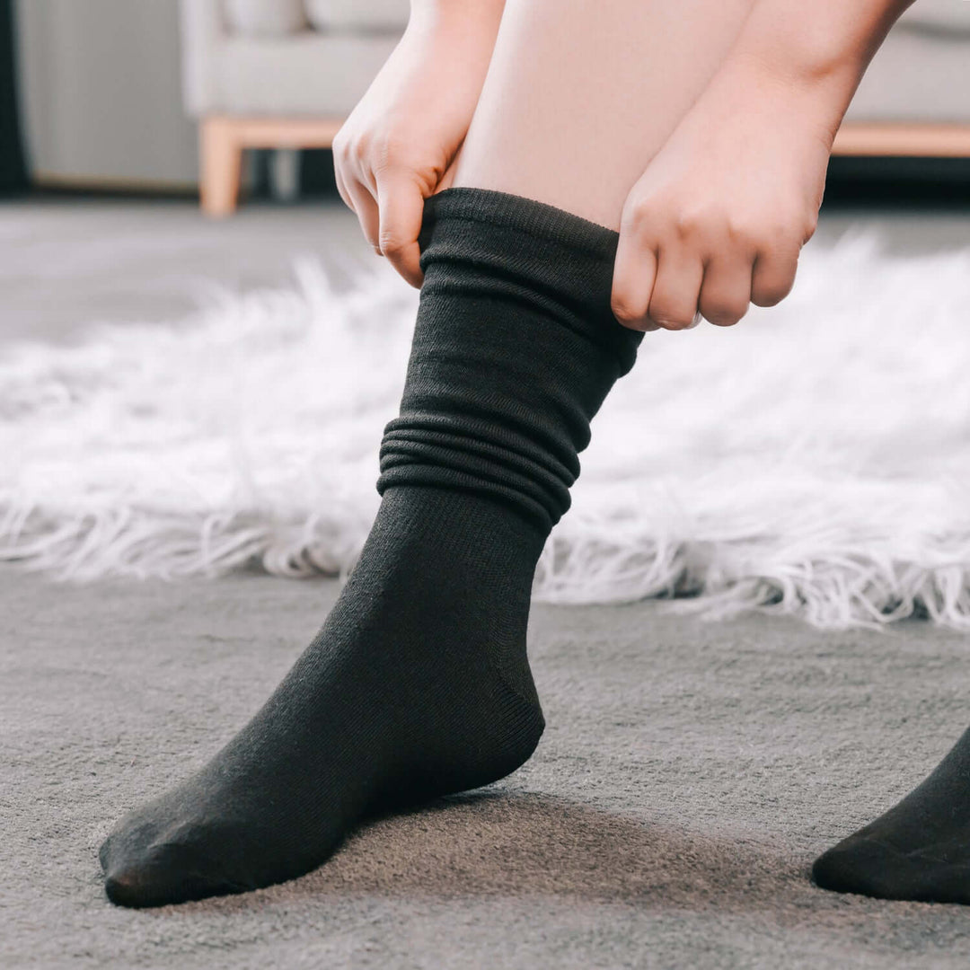 Person putting on large/XL black compression socks for everyday comfort and support.