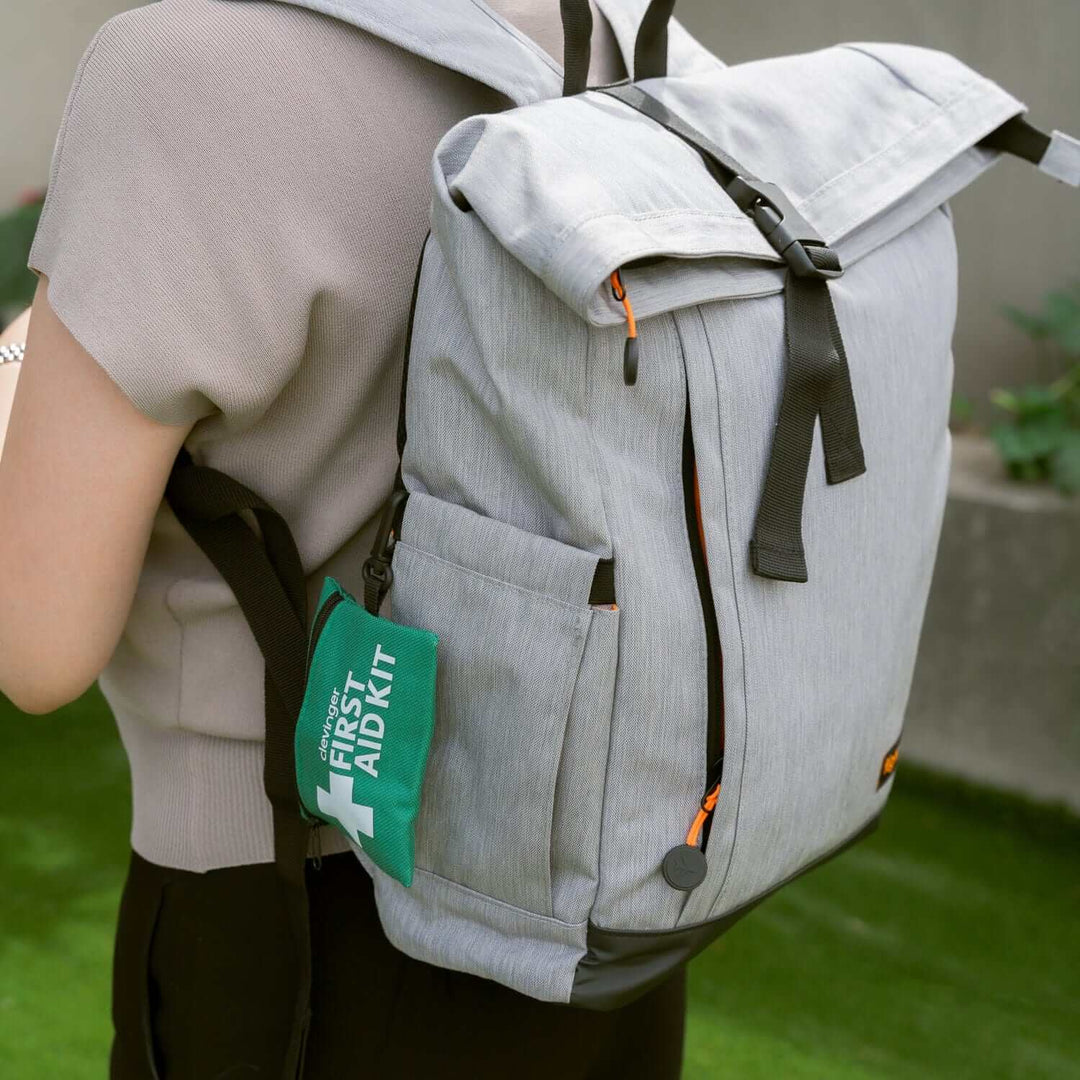 Mini emergency first aid kit attached to a stylish gray backpack, perfect for outdoor adventures and safety on the go.