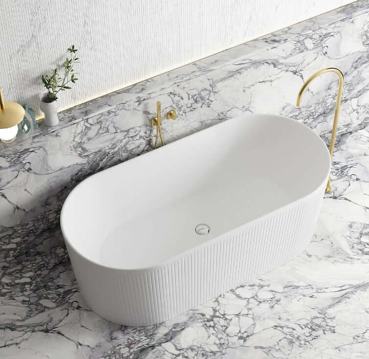 Modern oval freestanding acrylic bathtub in matte white on marble countertop with gold faucet. Affordable luxury for your DIY bathroom.