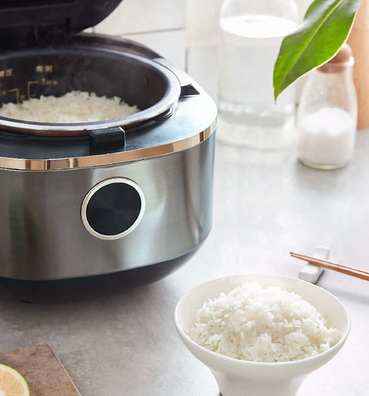 Joyoung Mini Rice Cooker with steaming rice and a bowl of cooked rice on a kitchen counter, highlighting its quality and design.