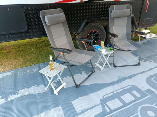 Two camping chairs on a recycled mat with a drink and snacks, set up for a relaxing outdoor experience.